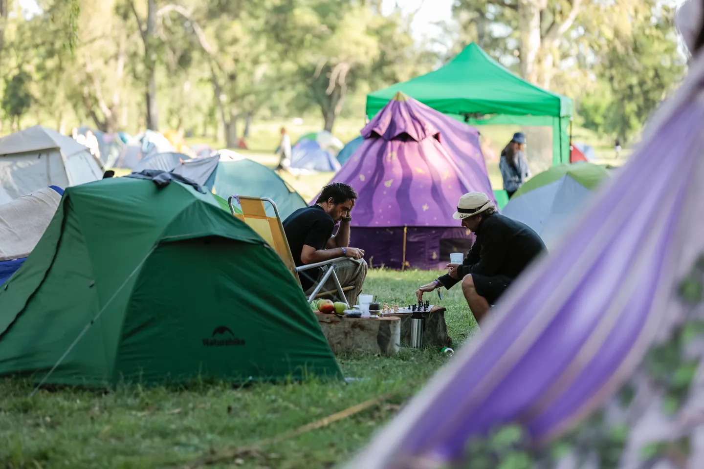 Dos personas jugando al ajedrez entre carpas en el camping de Amanita